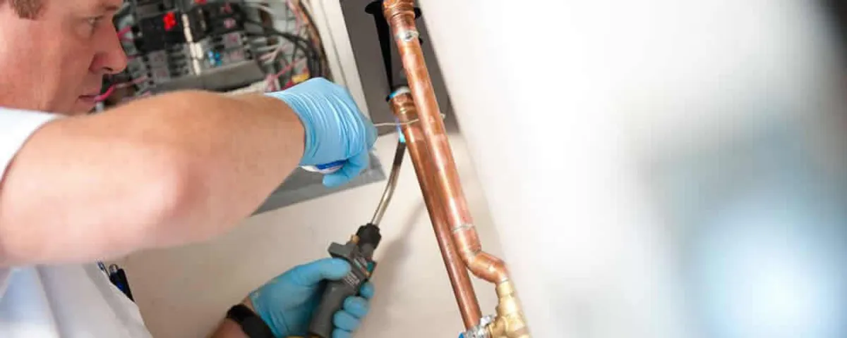 Water heater repair technician testing copper pipe connections and controls in Mountain View, CA